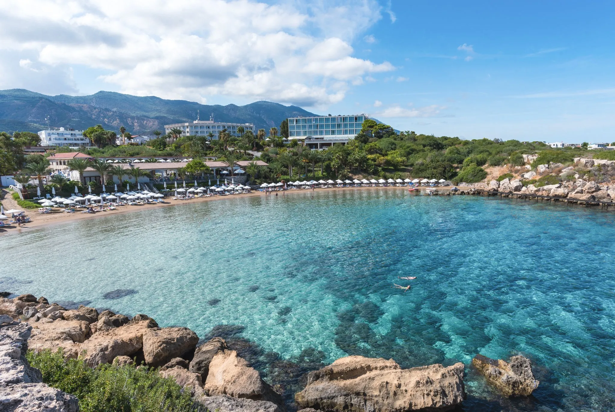 Luxury private taxi arriving at Denizkizi Hotel, an iconic beachfront resort in Alsancak, Kyrenia, featuring a beautiful sandy bay